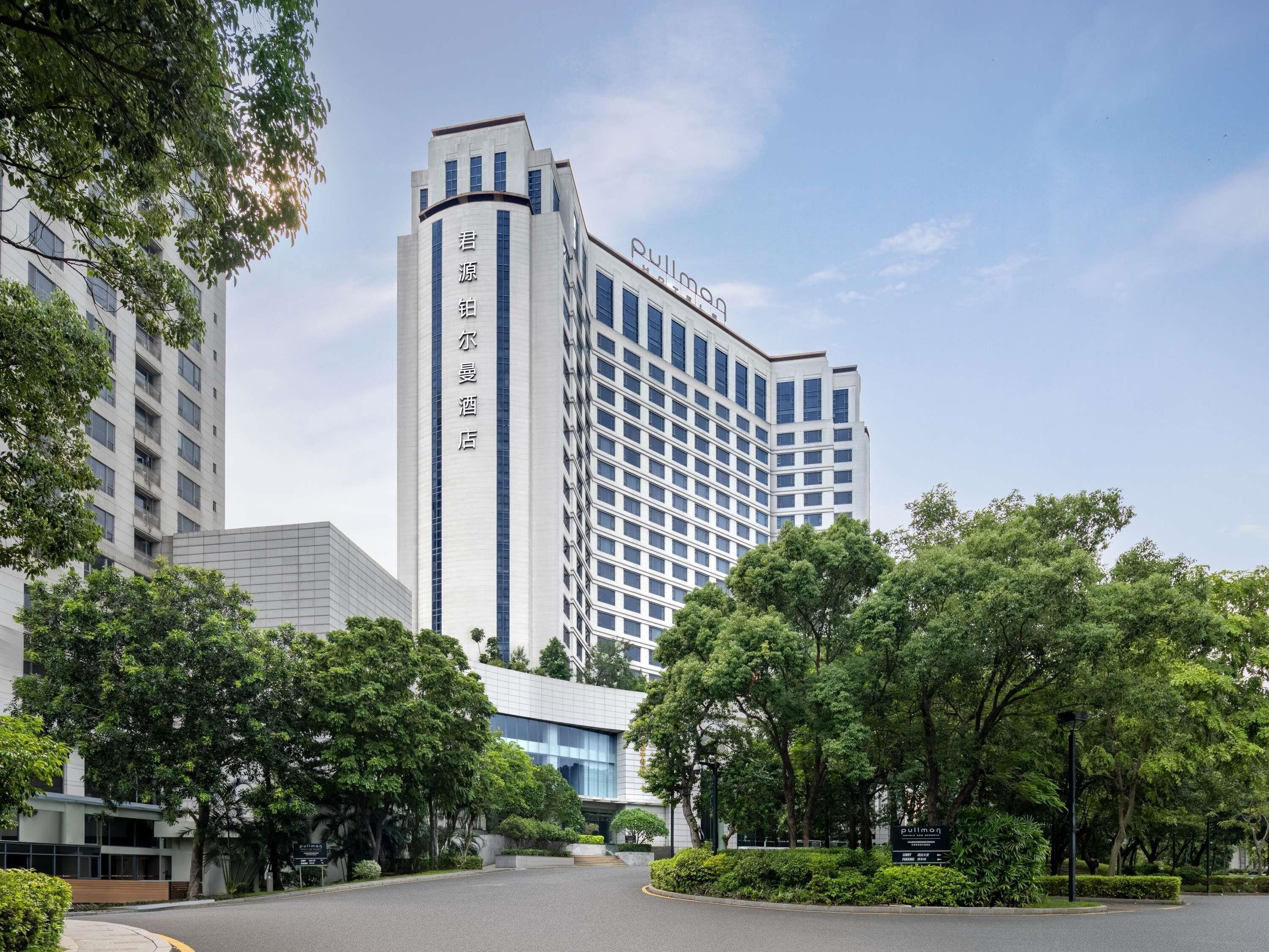 A hotel with a prominent tower, surrounded by lush greenery and a well-maintained courtyard.