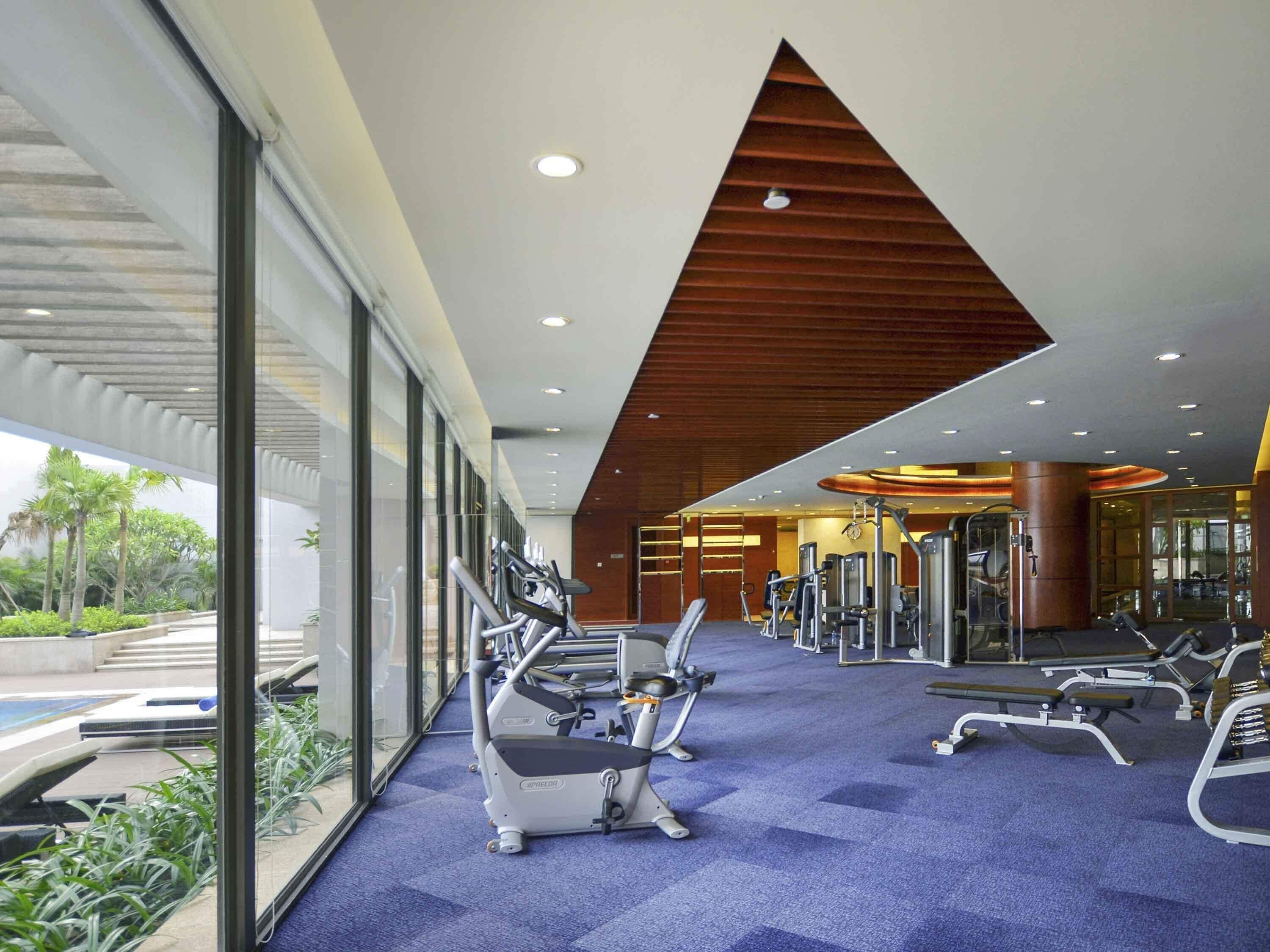A gym with cardio machines, weight equipment, and a view of greenery outside.