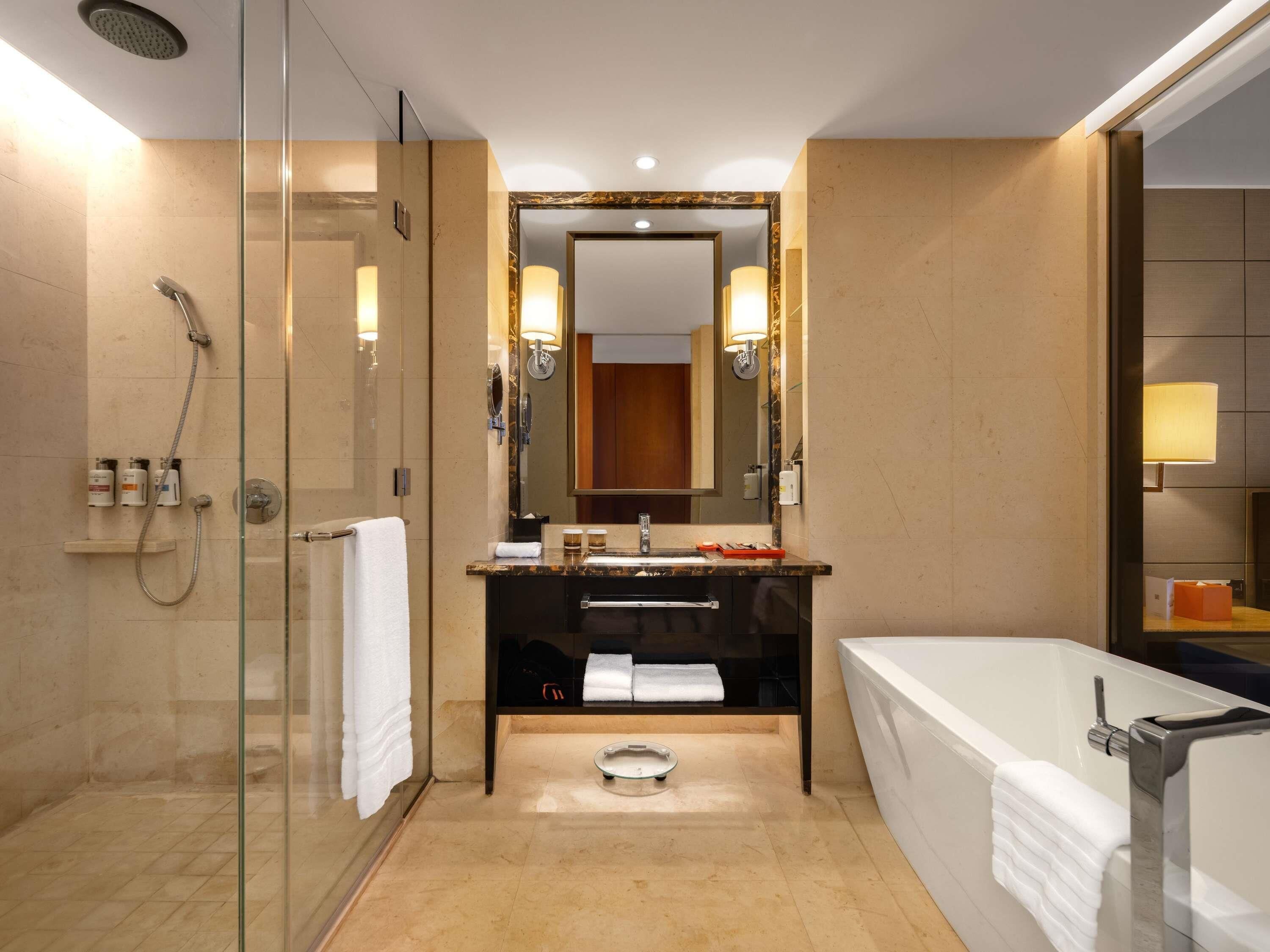 A modern bathroom with a glass-enclosed shower, a vanity with a mirror, a bathtub, and a toilet.