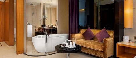 Une salle de bain moderne avec une baignoire sur pieds, un meuble-lavabo avec un miroir et un canapé avec des coussins.