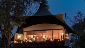 A tented accommodation with a balcony, large windows, and interior lighting. - Banjaar Tola, Kanha National Park (Baihar)