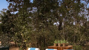 Un espace aménagé au bord de la piscine, avec des chaises longues et des coussins en bois, une table en bois et une rangée de bougies.