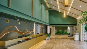 A reception area with a curved counter, modern pendant lighting, and a green wall.