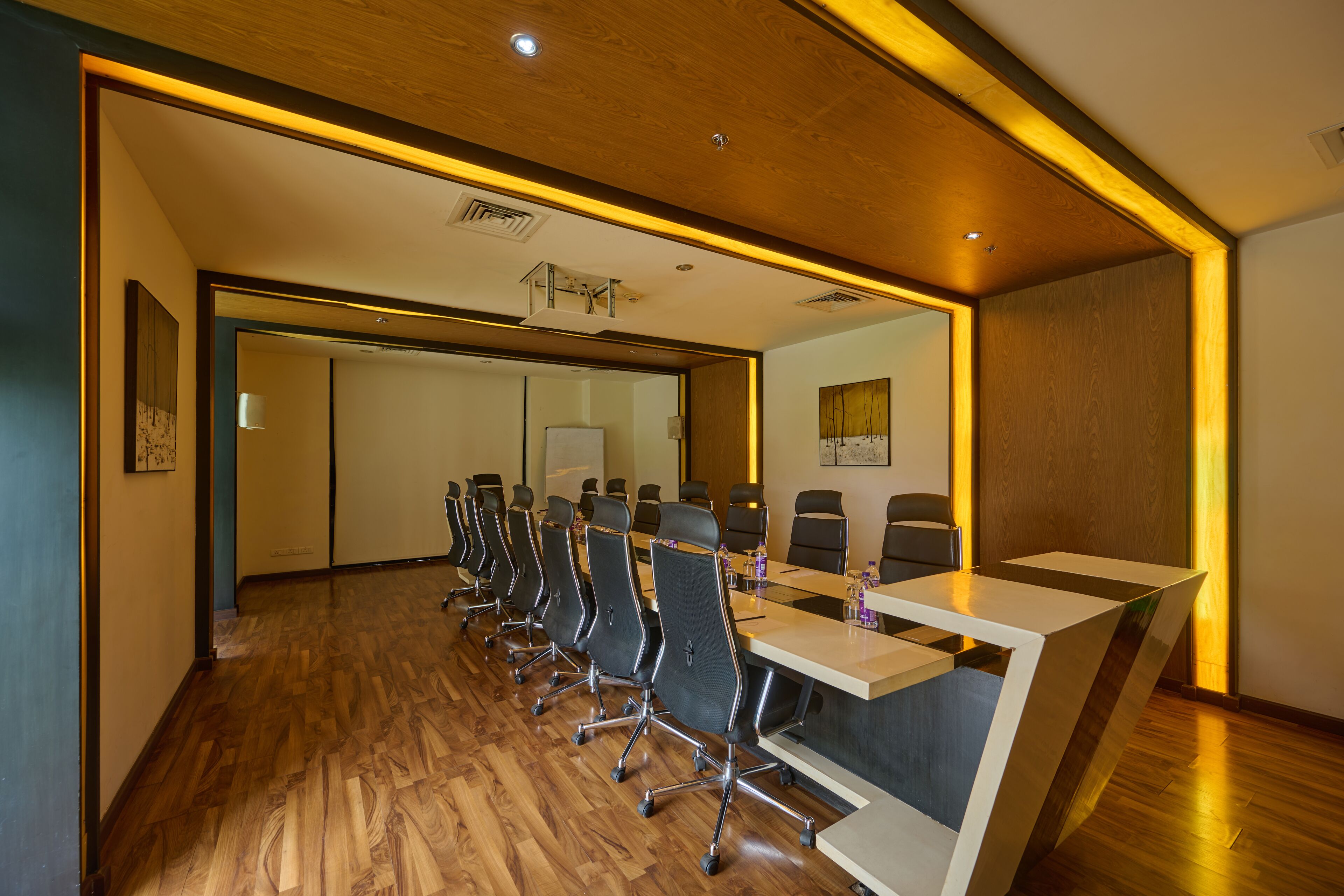 A conference room with a long table, multiple chairs, and a wooden floor.