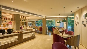 A modern restaurant with a buffet area, seating with red chairs, and decorative plates on the wall.