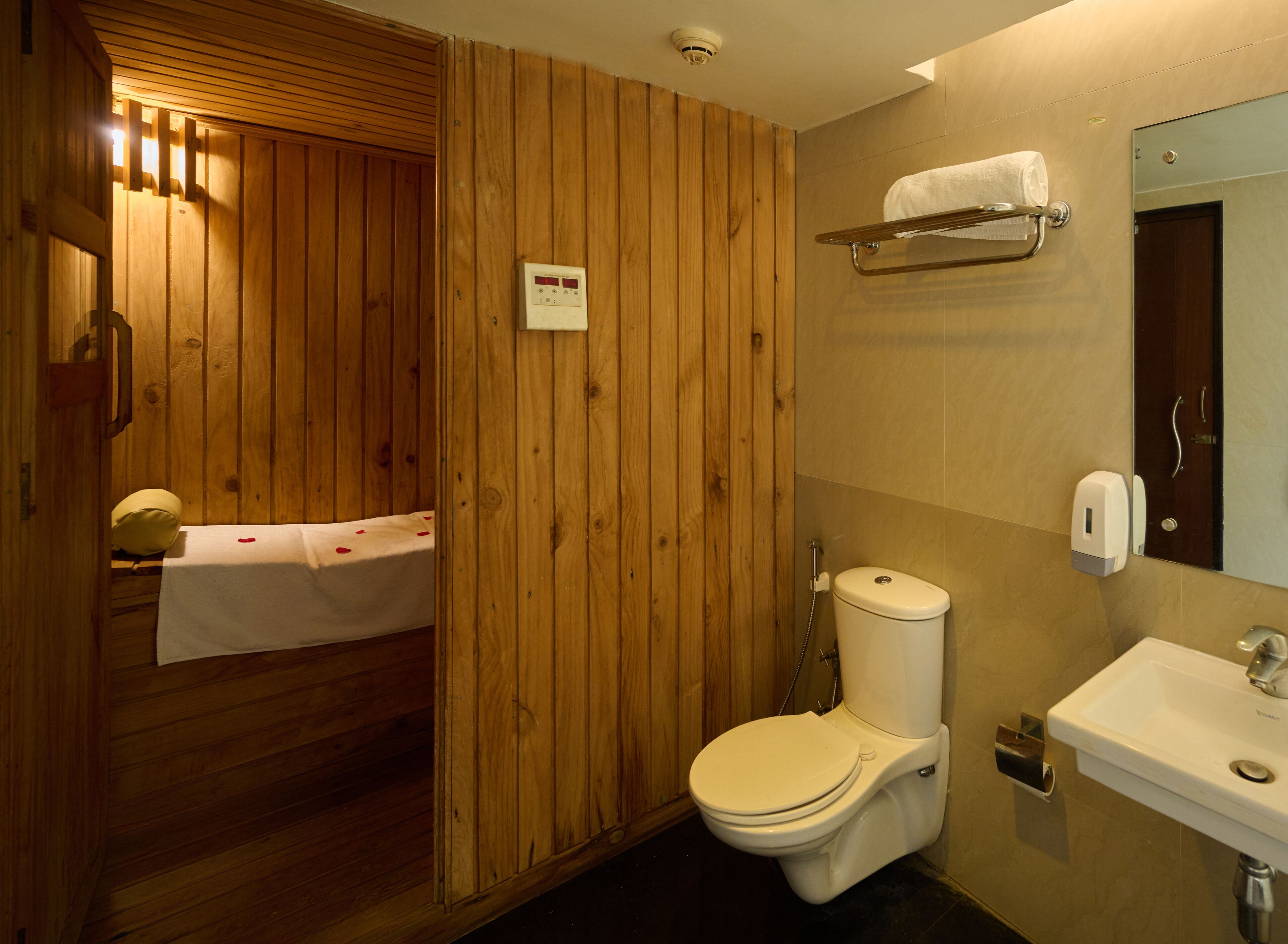 Een badkamer met houten lambrisering, een toilet, een wastafel en een handdoekhouder.