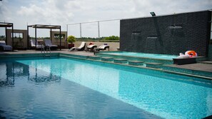 Une piscine avec des chaises longues et un mur en pierre.