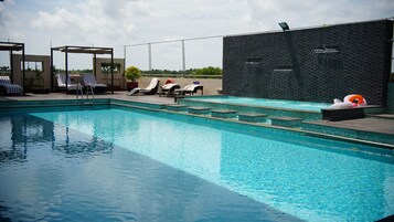 Una piscina al aire libre, sombrillas, sillones reclinables de piscina