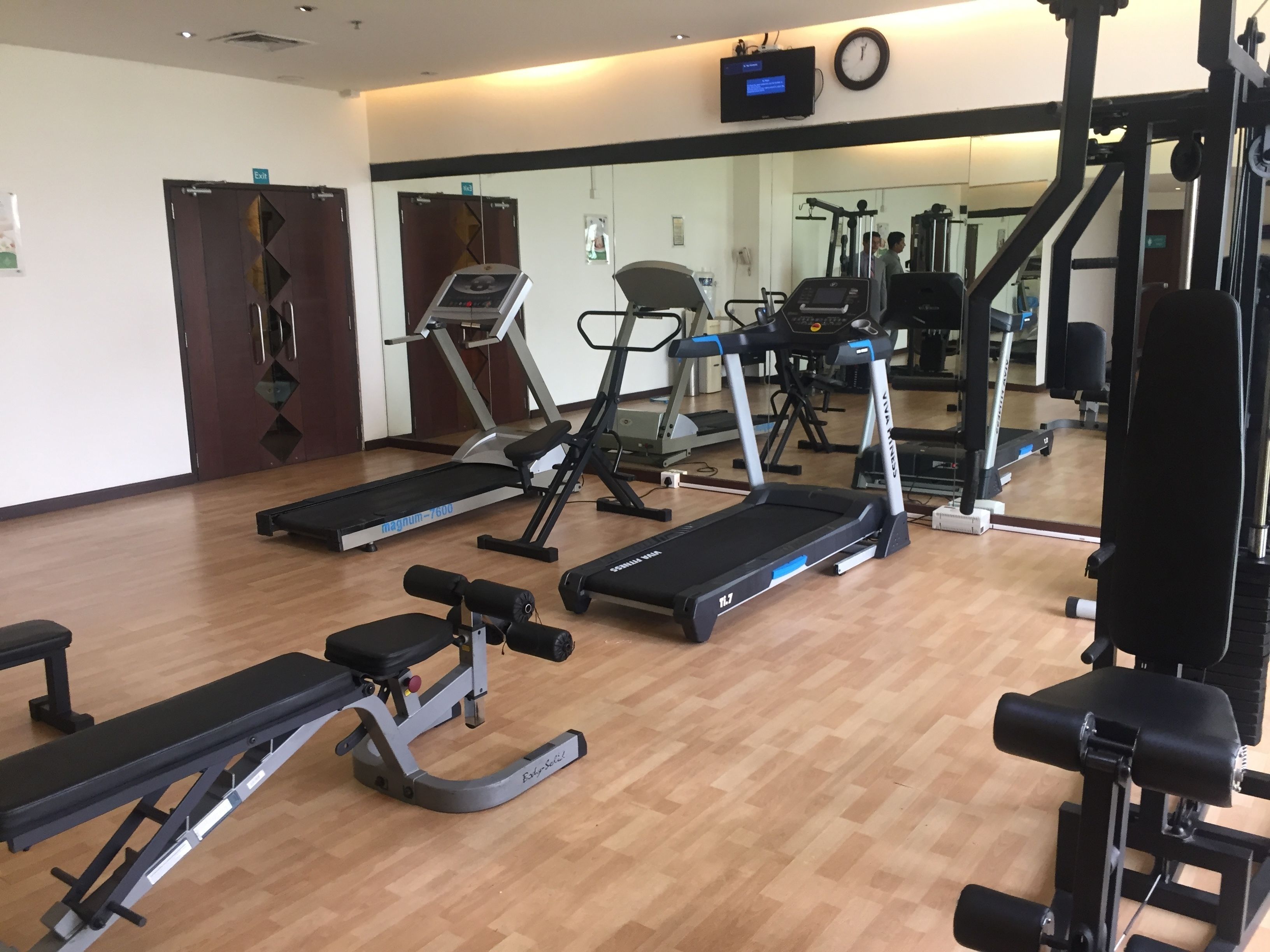 A gym with treadmills, weight machines, and a mirror reflecting the equipment.
