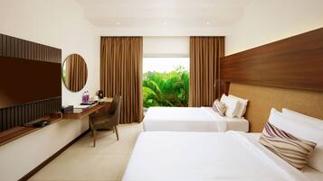 Une chambre d’hôtel avec deux lits, un bureau, une chaise, une télévision et une vue sur la verdure.