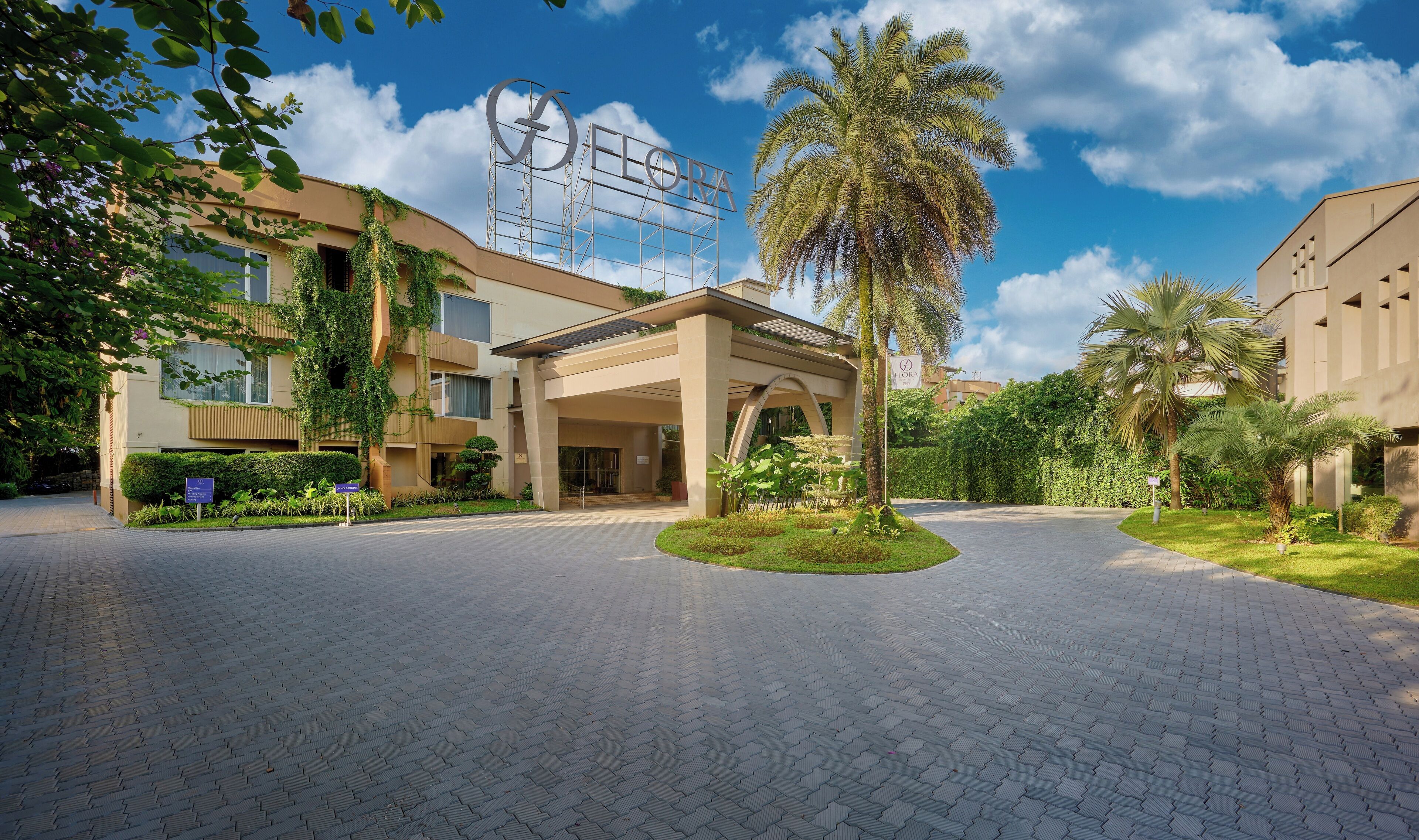 A hotel entrance with a paved driveway, palm trees, and a sign reading "ELORA".