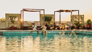 A rooftop pool area with lounge chairs and a pergola structure.