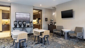 A hotel lobby with a coffee station, seating area, and a TV mounted on the wall. - Residence Inn Midland Marriott (Midland)