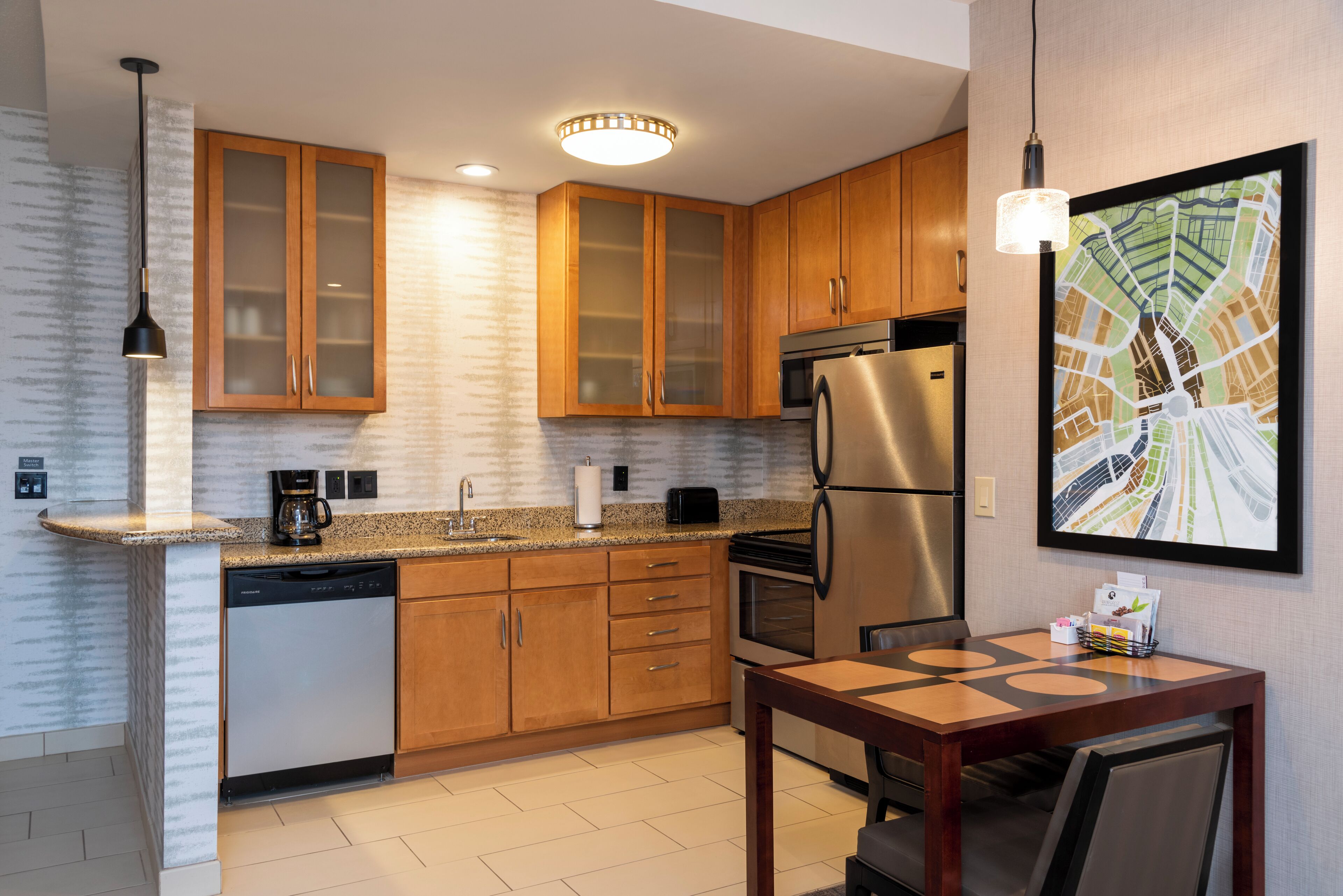 A modern kitchen with wooden cabinets, a stainless steel refrigerator, a dishwasher, and a dining area with a table and chairs.