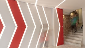 Un intérieur moderne avec un escalier et un mur orné de motifs lumineux géométriques.