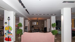 Un vaste espace de vie agrémenté d’un grand canapé rose, d’un parquet en bois et d’une décoration moderne, notamment une œuvre d’art représentant une guitare aux couleurs vives.