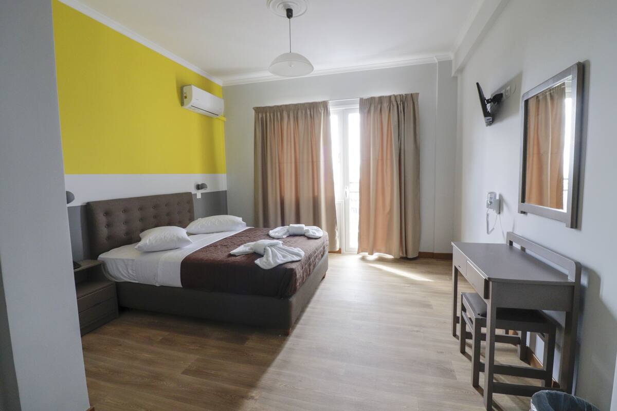 A bedroom with a bed, bedside table, and a desk with a chair.