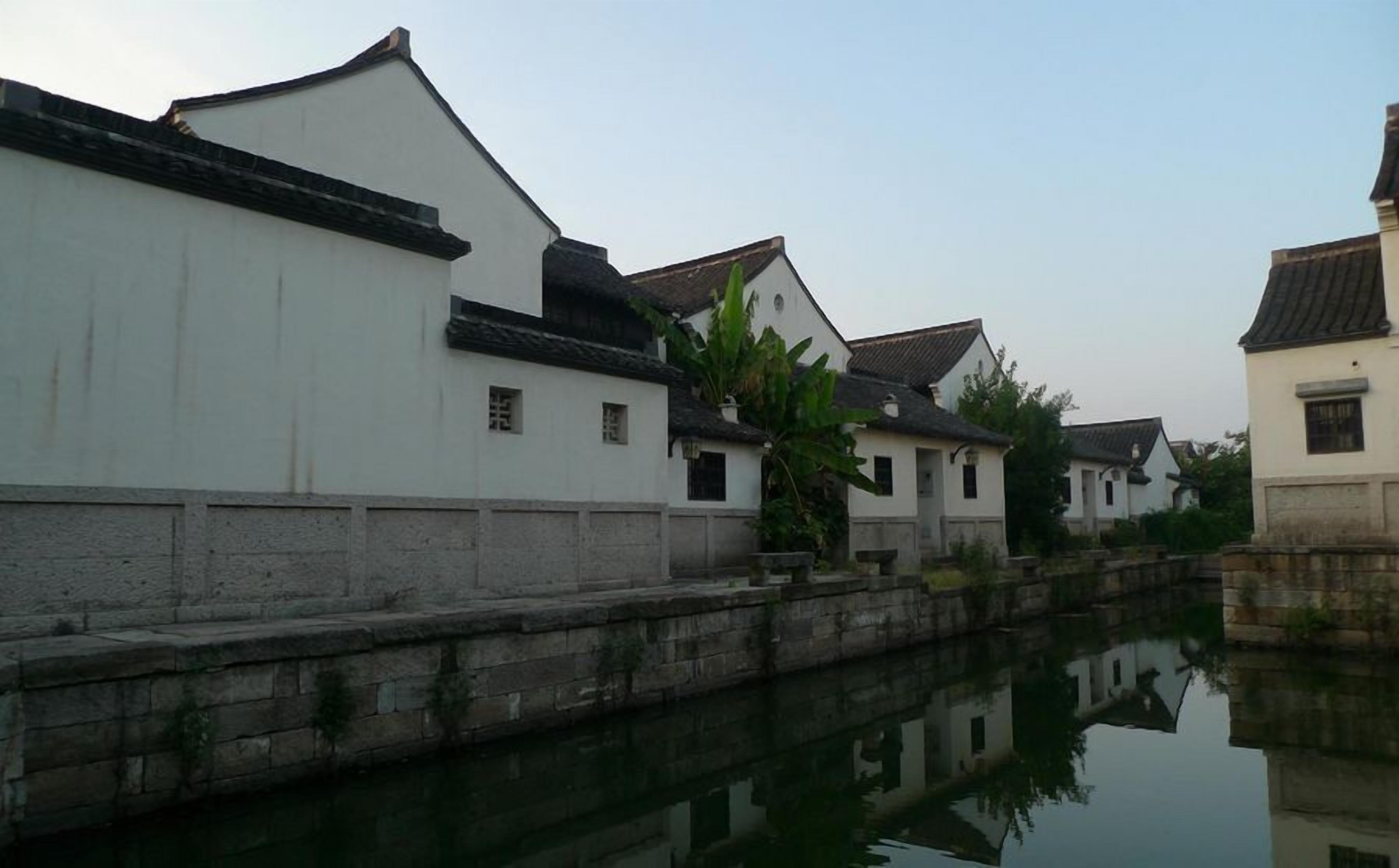 A traditional canal-side building with a white facade and tiled roofs.