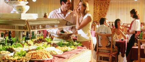 A buffet setup with various food items and a serving staff.