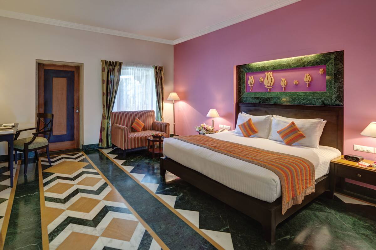 Une chambre d’hôtel avec un grand lit, un bureau, une chaise et une fenêtre avec des rideaux.