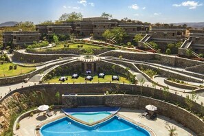 A resort with a central pool, multiple guest rooms, and a landscaped garden.
