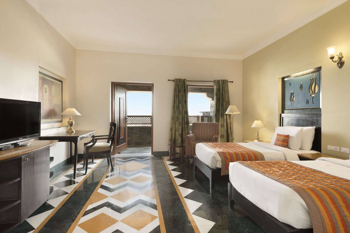 Une chambre d’hôtel avec deux lits, un bureau, une télévision et une vue sur la ville.