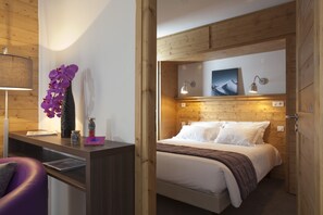 A wooden-paneled room with a bed, a desk with a lamp, and a purple chair. - Le Chalet du Mont Vallon Spa Resort (Les Belleville)
