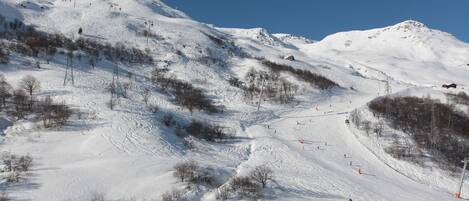 A snow-covered ski slope with ski lifts and a clear sky.