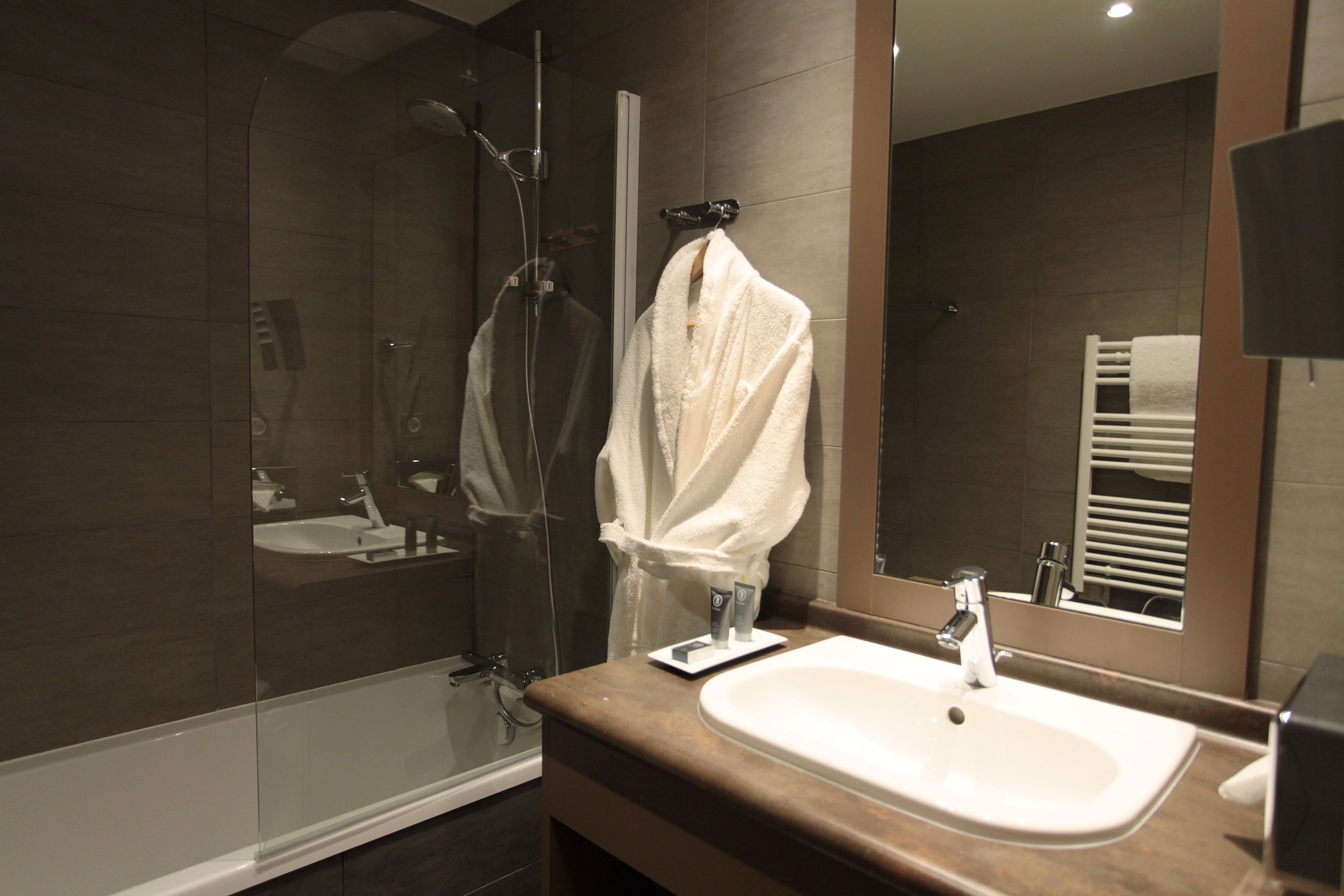 A modern bathroom with a glass-enclosed shower, a white sink, and a large mirror.