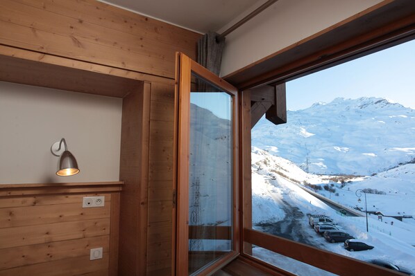 Un interior de madera con un amplio ventanal que da a un paisaje montañoso cubierto de nieve.