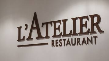 Letrero para 'L'Atelier Restaurant' con diseño moderno.