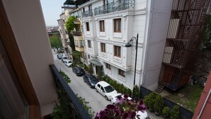 A street view of a residential area with parked cars and a building with balconies.