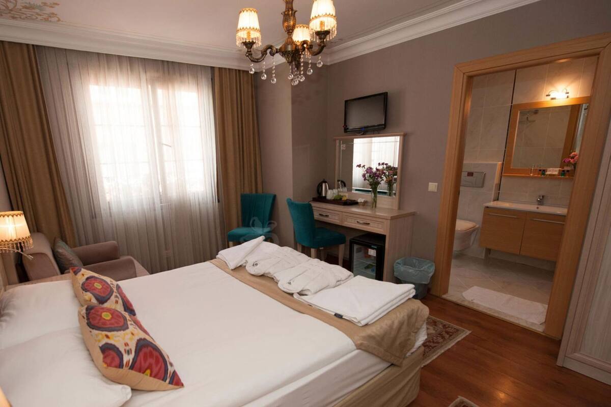 A hotel room with a bed, a desk, a chair, a TV, and a bathroom.