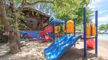 Children can play on colorful slides and climbing structures surrounded by trees in a shaded area.