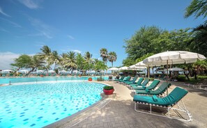 A swimming pool with lounge chairs and umbrellas, surrounded by palm trees. - Regent Chalet Hua Hin (Cha-am)