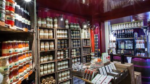 Een winkel met schappen vol potten en flessen, een toonbank met wijnflessen en een vat.