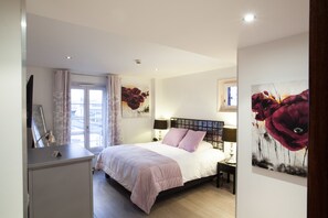 Relax in a serene bedroom with a large bed, bedside table, and wall-mounted artwork.