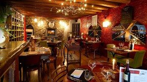 Een gezellig restaurant met houten inrichting, stenen muren en diverse eettafels en stoelen.