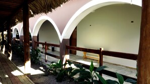 Un espacio al aire libre techado con un sendero de ladrillo, una valla de madera y arcos.