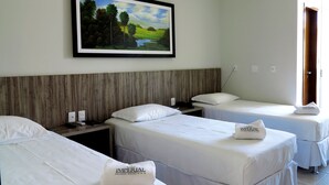 Habitación de hotel con dos camas, cabecero de madera, un cuadro de un paisaje y una puerta a la derecha.