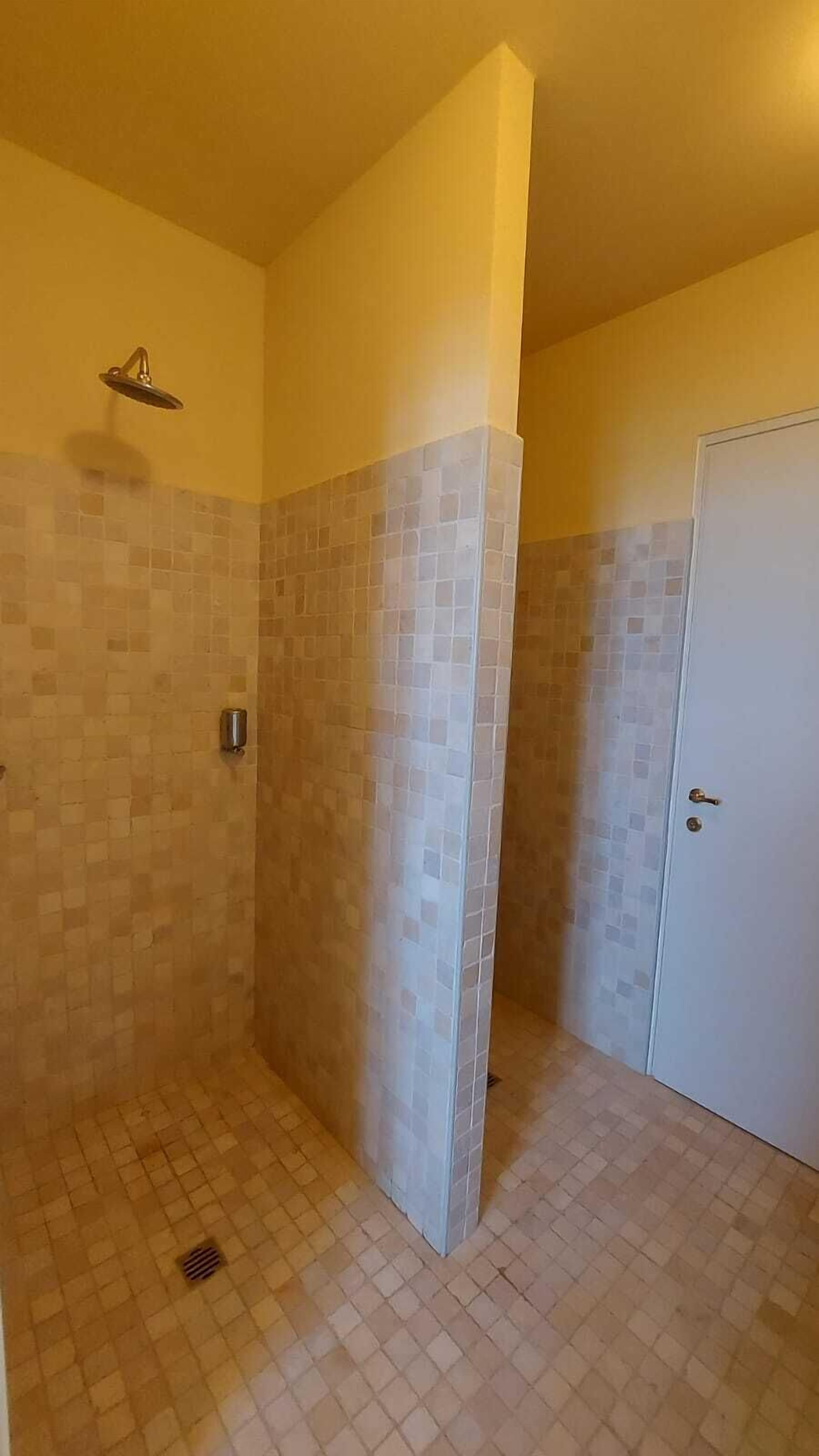 A bathroom with a shower, tiled walls, and a door.