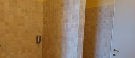 A bathroom with a shower, tiled walls, and a door.