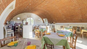 A spacious dining area with multiple tables and chairs, a kitchen in the background, and a brick ceiling. - Le Sodole Country Resort & Golf (Pontedera)