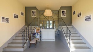 A staircase with a white railing, a wooden chair, and a table with a vase of flowers. - Le Sodole Country Resort & Golf (Pontedera)
