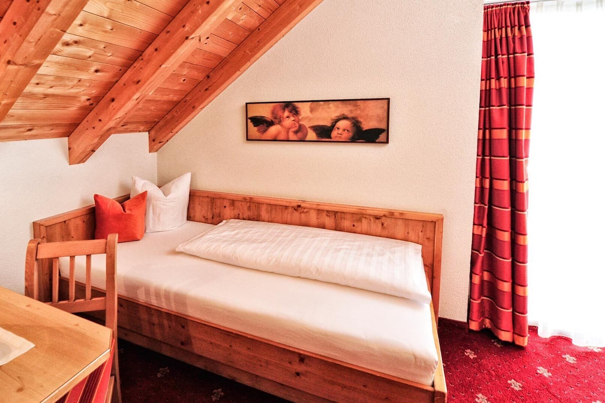A cozy room with a wooden bunk bed, a small table with a candle, and a framed picture on the wall.