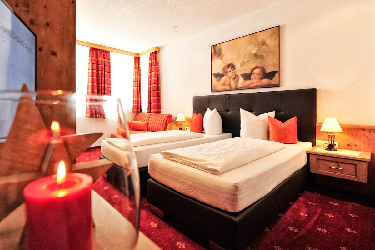 A hotel room with two beds, a painting, a wooden headboard, and a red carpet.