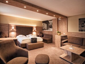 Una habitación de hotel moderna con techo de madera, una cama, un sofá, una mesita de centro y un televisor montado en la pared.