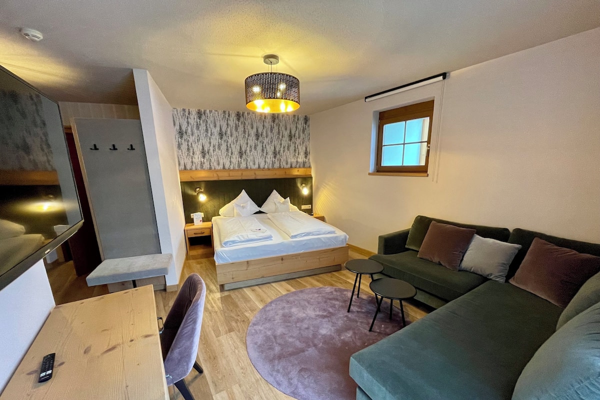 Une chambre à coucher moderne avec un lit, un canapé vert, une petite table et un bureau.