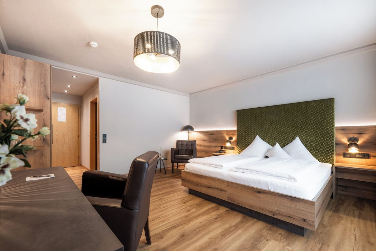 Une chambre d’hôtel moderne avec un lit en bois, un bureau et une chaise.