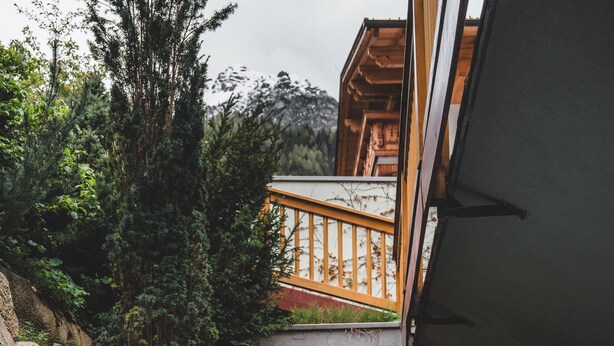A person in a hot tub with a view of a wooden deck and greenery. - Alpin Resort Stubaierhof (Fulpmes)